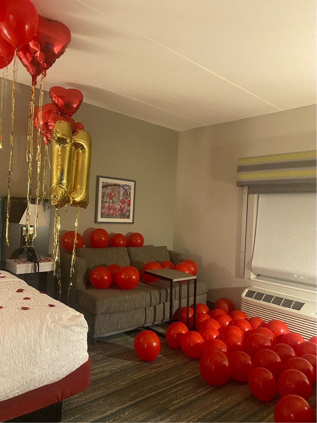 Hotel suite filled with red balloons and gold number balloons