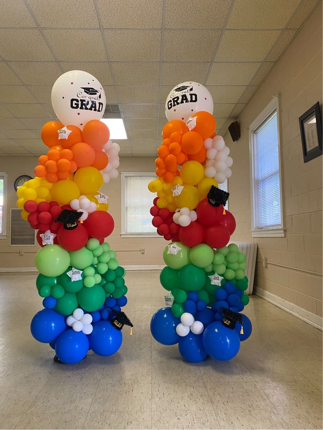 Rainbow balloon columns topped with graduation balloons