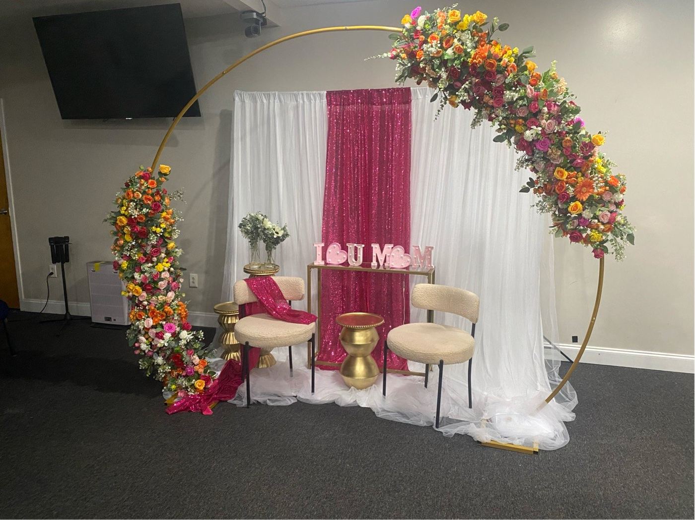 Gold hoop arch with bright florals and a sequin backdrop