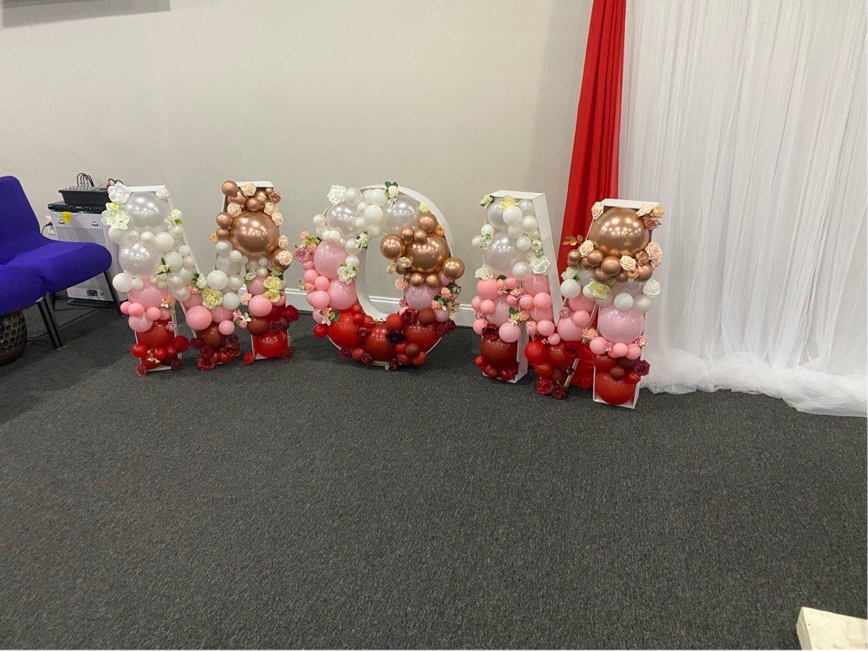 Balloon marquee letters spelling MOM with red and rose gold balloons