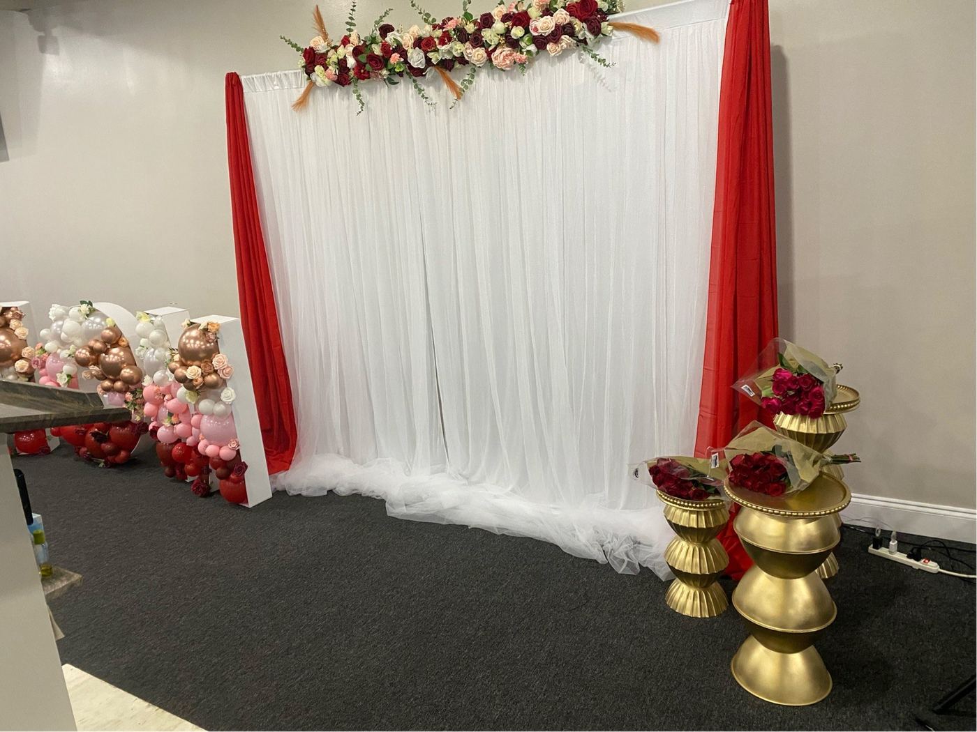White draped backdrop with red accents and gold pedestals